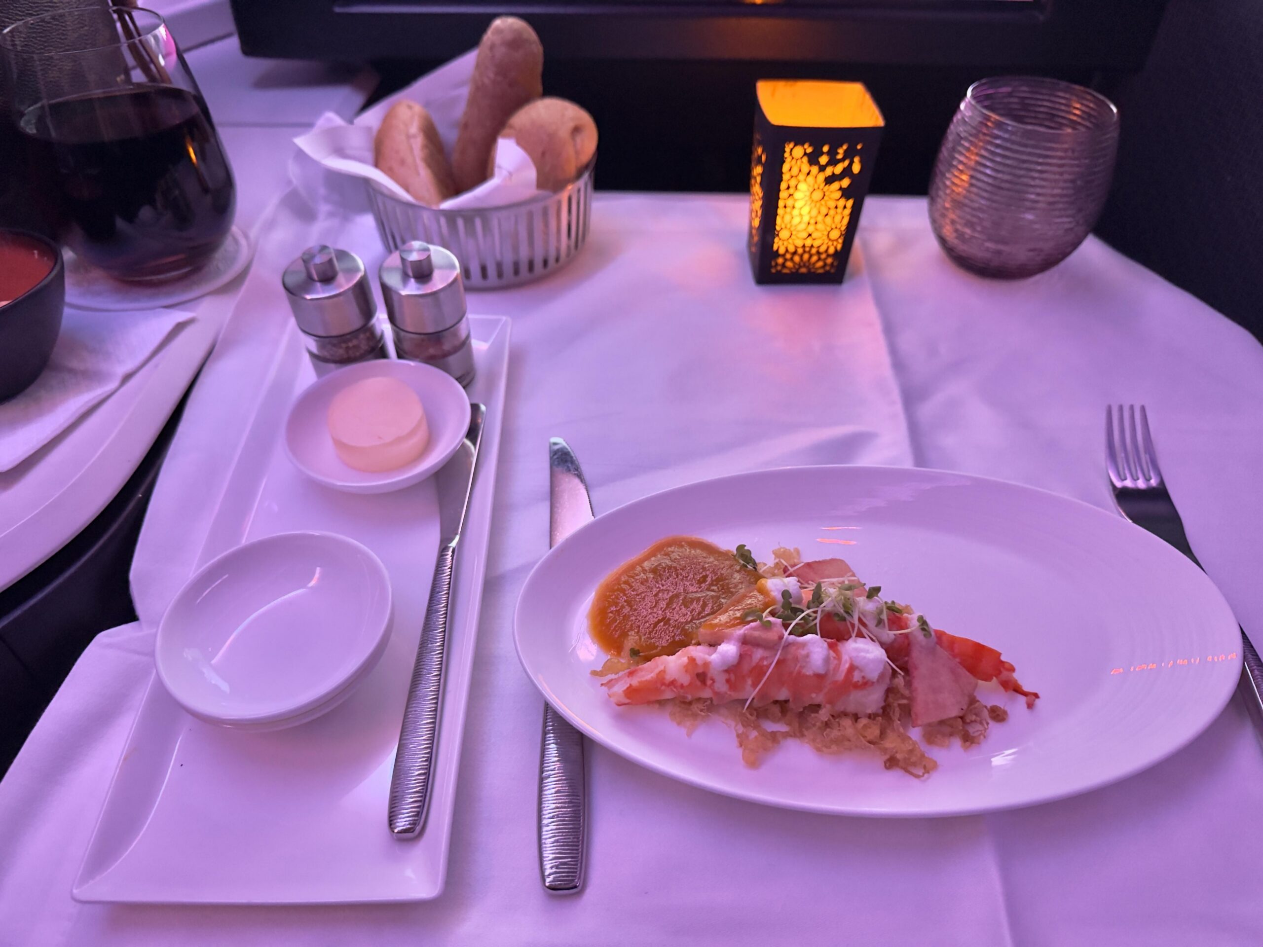 Luxuriös serviertes Hummergericht mit Kokosflocken und Brot in der Business Class eines Flugzeugs