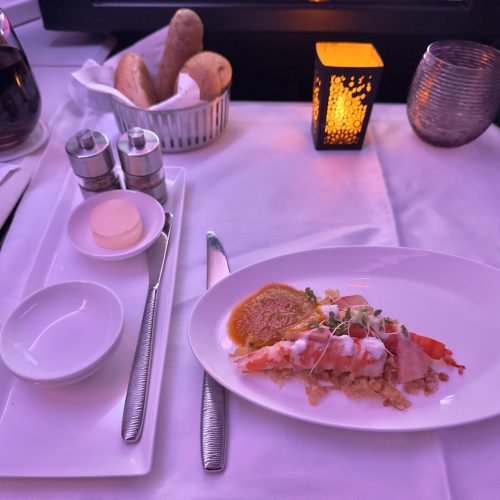 Luxuriös serviertes Hummergericht mit Kokosflocken und Brot in der Business Class eines Flugzeugs