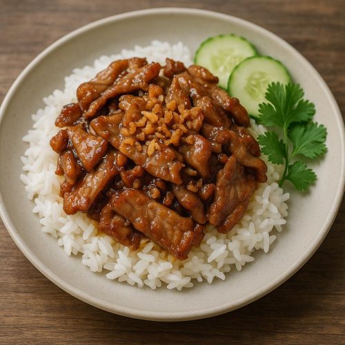 Moo Kratiem Prik Thai auf Jasminreis mit knusprigem Knoblauch, Gurkenscheiben und Koriander – authentisches Thai-Rezept