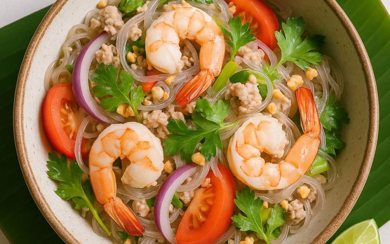 Authentischer Yam Woon Sen Glasnudelsalat mit Garnelen, Schweinehack, Koriander, Sellerie, Tomaten und Erdnüssen auf Bananenblatt – frisch, würzig, thailändisch